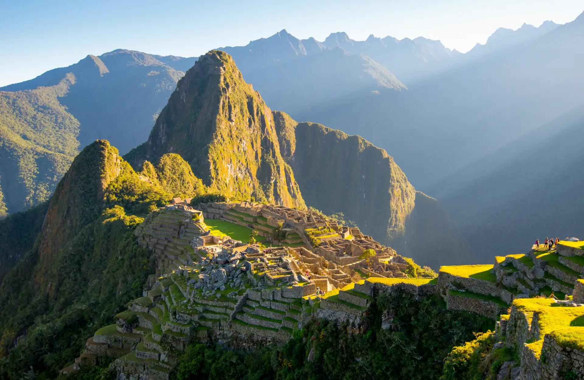 Machu Picchu: La Maravilla Inca en lo Alto de los Andes Cusco Histórico - Vista panorámica de Machu Picchu con montañas verdes y nubes alrededor.