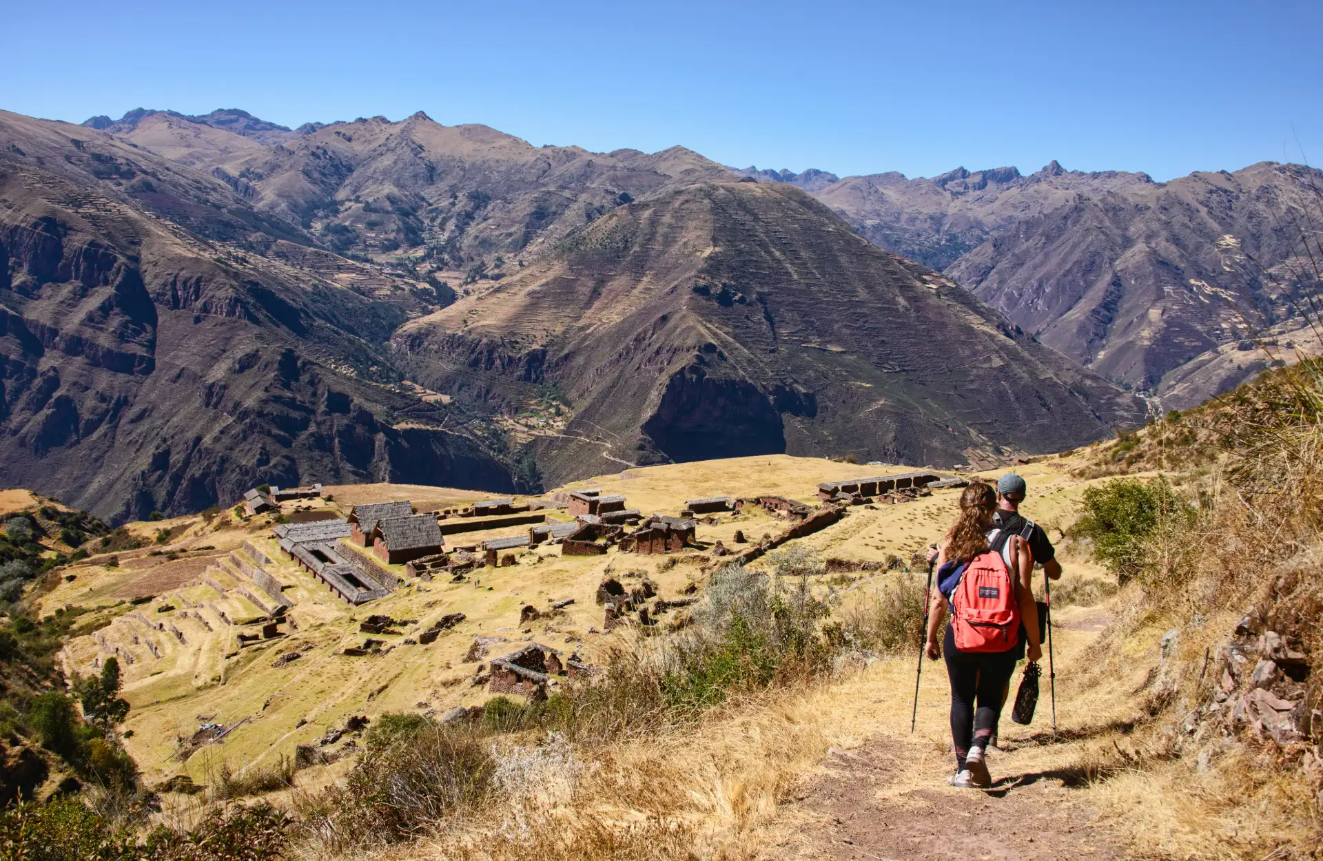 Huchuy Qosqo Full Day: Explora las Ruinas Incas en lo Alto de los Andes Vista panorámica de las ruinas de Huchuy Qosqo con el Valle Sagrado de fondo, rodeado de montañas.