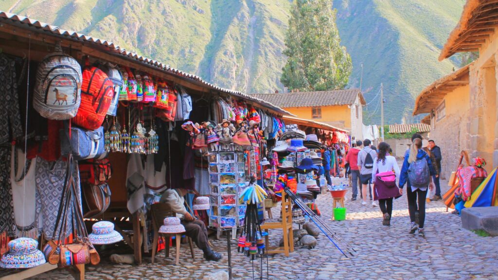 Visitantes recorriendo los coloridos puestos del Mercado de Ollantaytambo