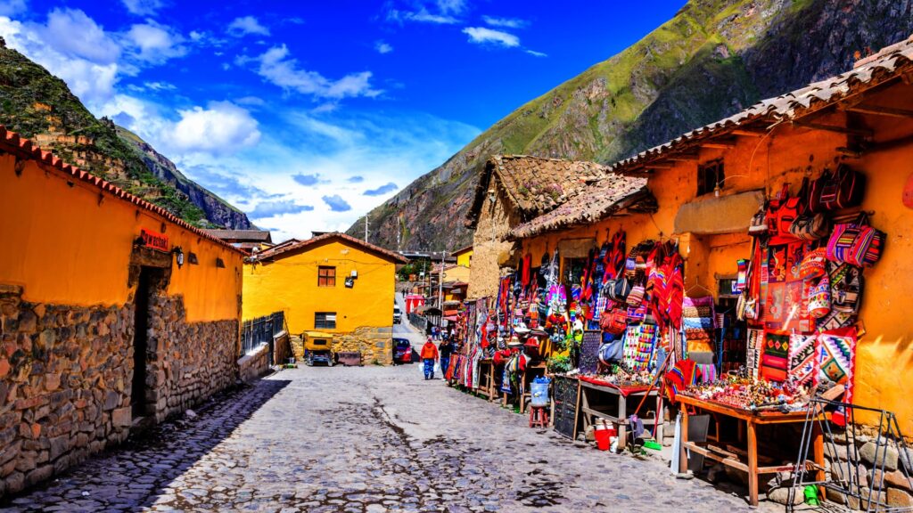 Mercado de Ollantaytambo con puestos de textiles coloridos y productos artesanales.