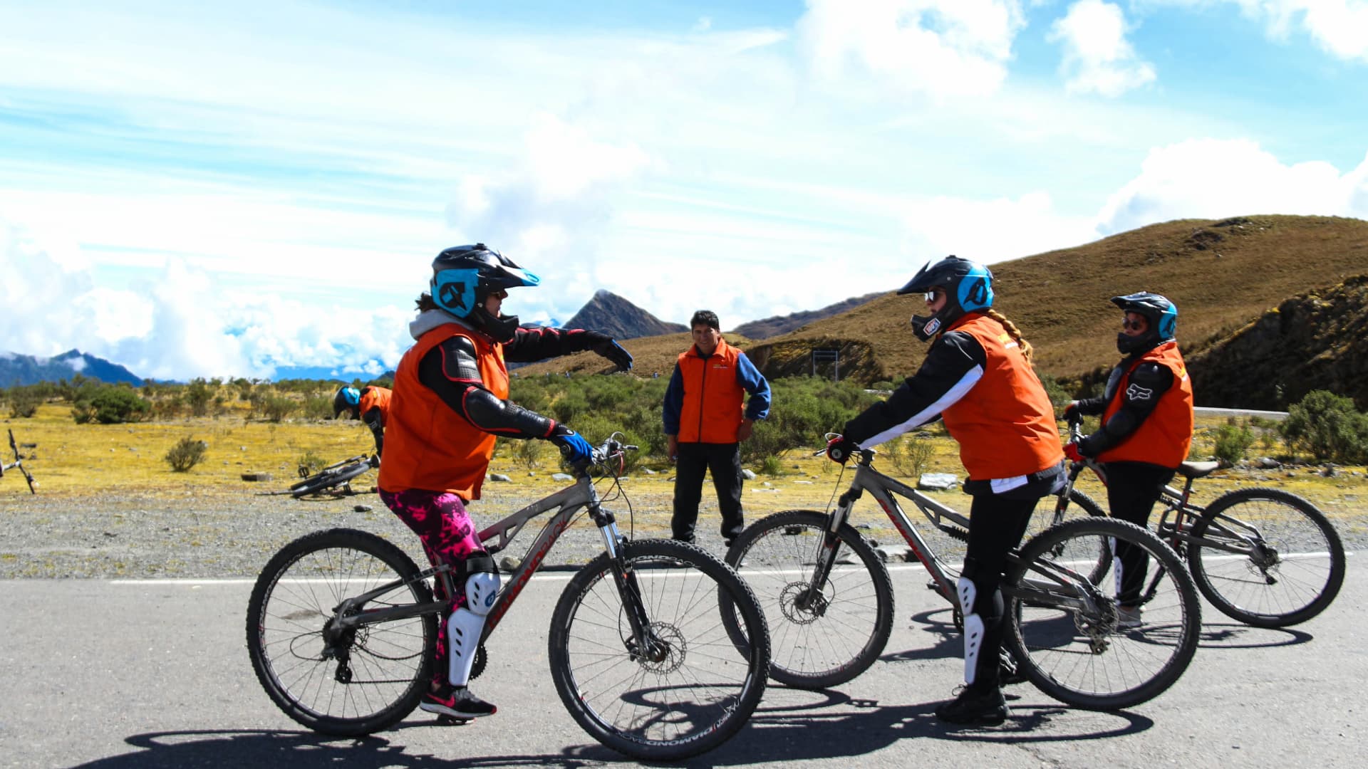 Aventura en Bicicleta de Montaña por los Andes de Cusco Un grupo de viajeros con cascos y equipo de protección se prepara para un tour de ciclismo inka Jungle guiado en una carretera de alta montaña.